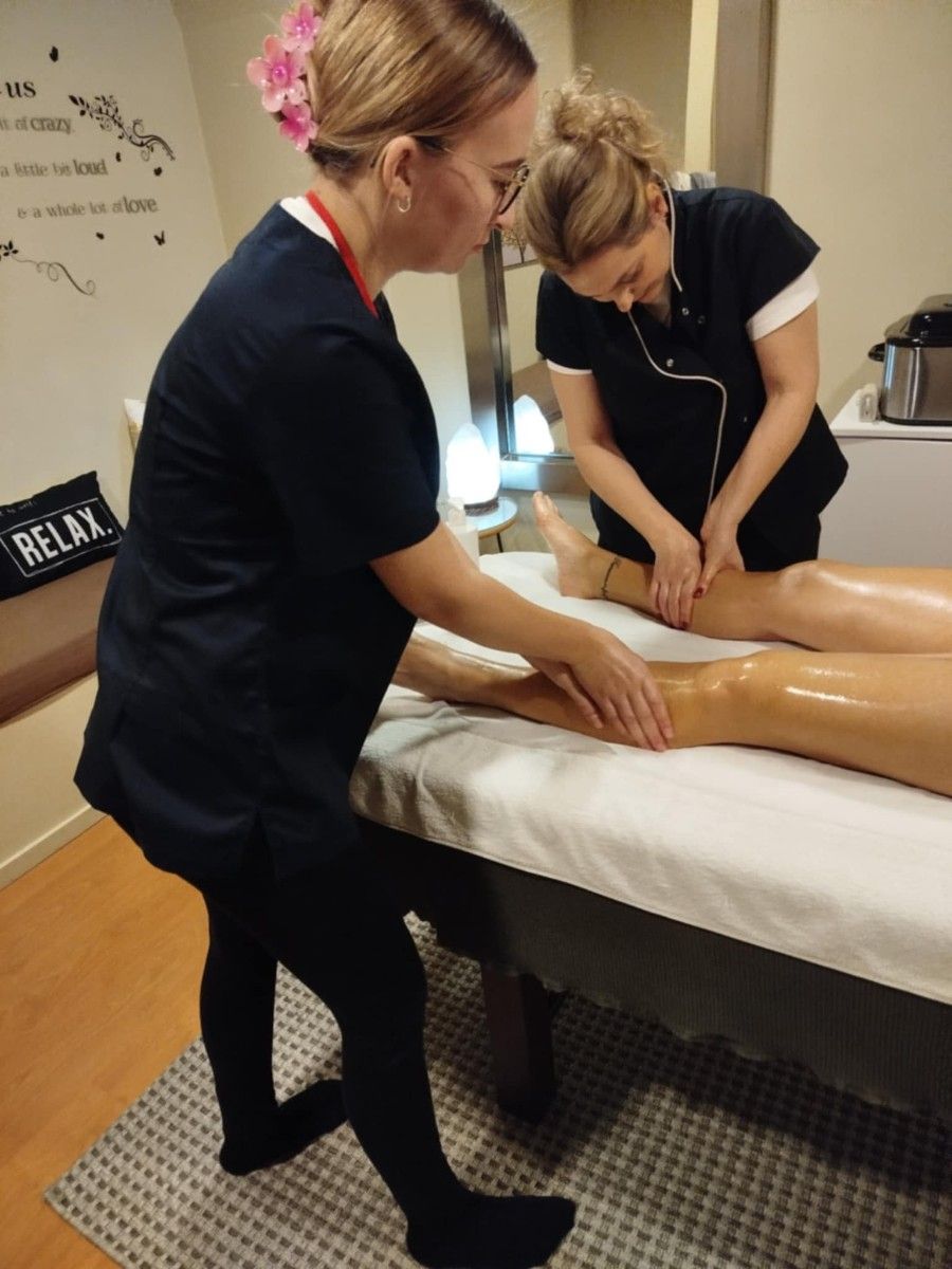 Panie wykonujące zabieg masażu nóg.