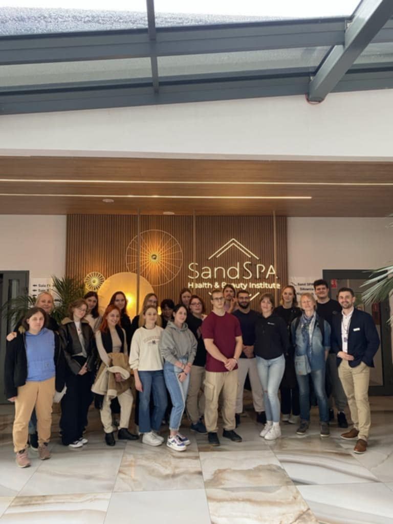 Grupowe zdjęcie na tle nazwy i wejścia do SPA.