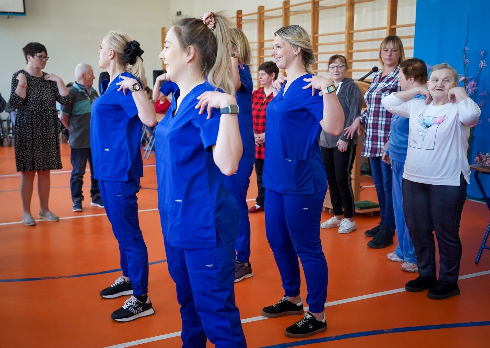 Uczniowie prowadzący wspólne ćwiczenia ruchowe na hali sportowej.