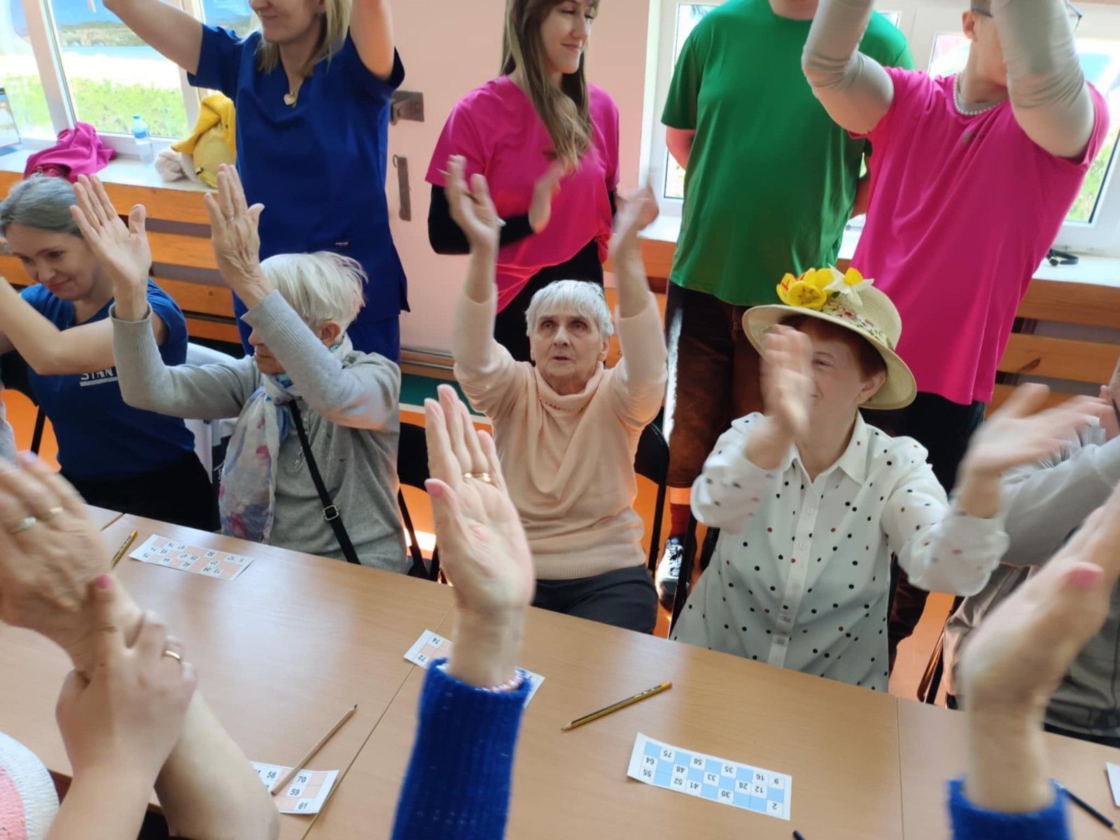 Widok na bawiących się seniorów przy stole wraz z uczniami.