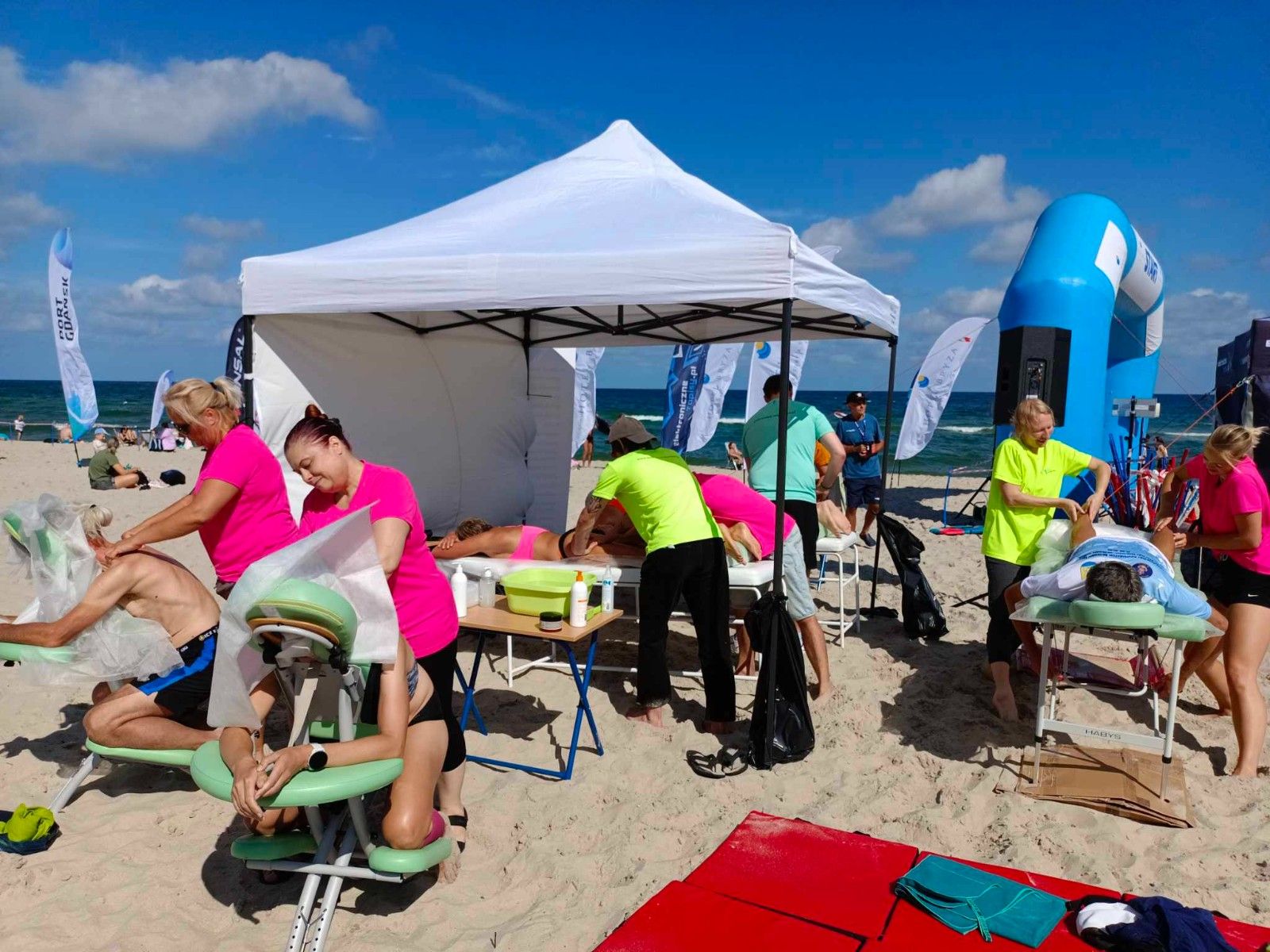 Uczennice masujące sportowców na plaży na krzesłach do masażu. 