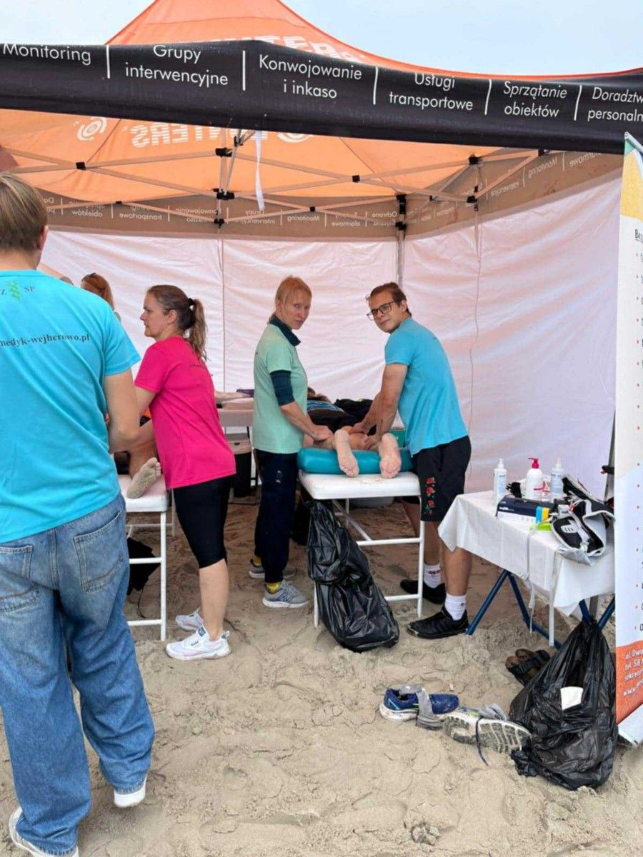 Masaż nóg na stole do masażu przez uczniów uczestnika maratonu.