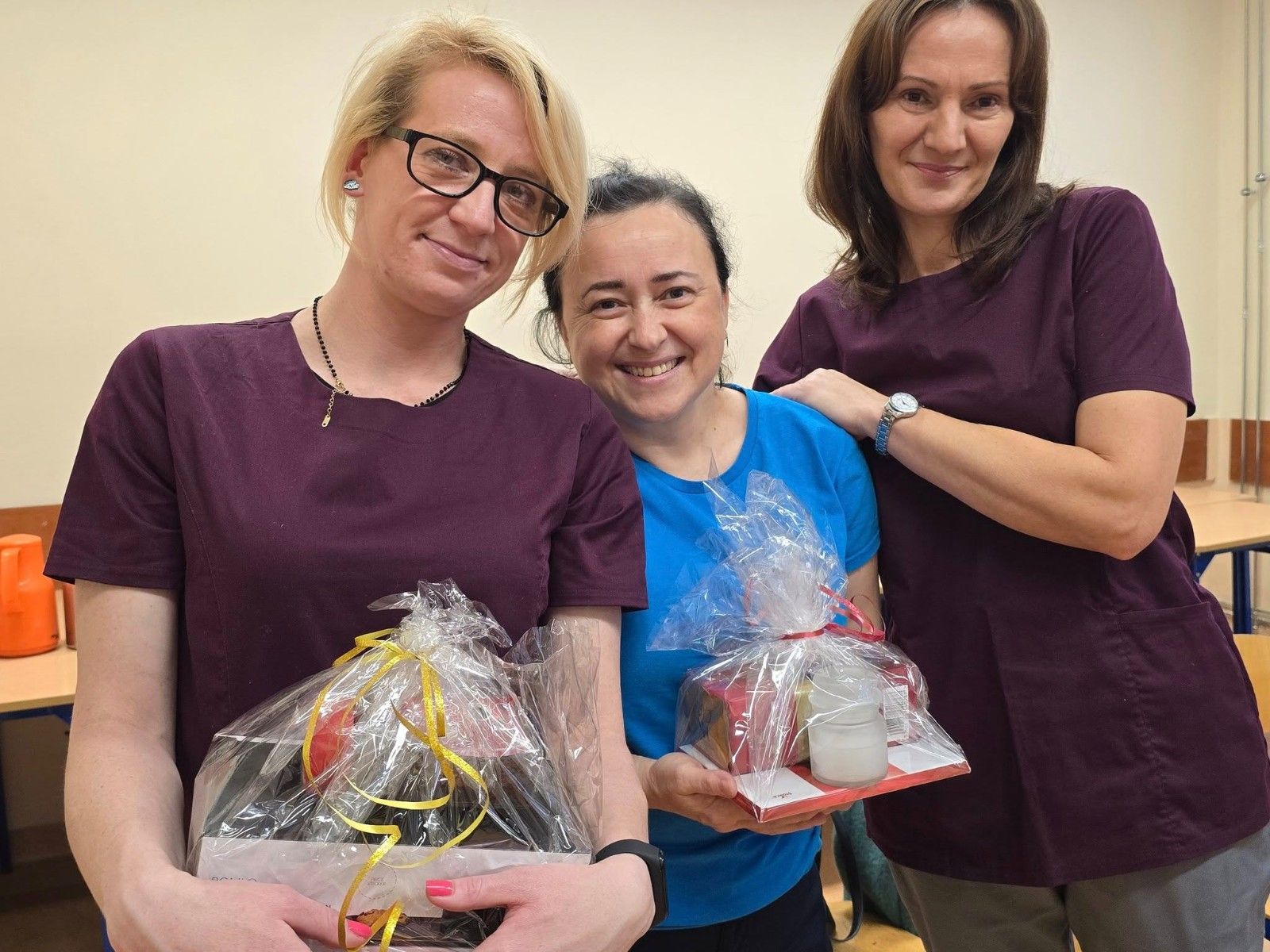 Wspólne zdjęcie trojga absolwentów po otrzymaniu upominków i dyplomów ukończenia.