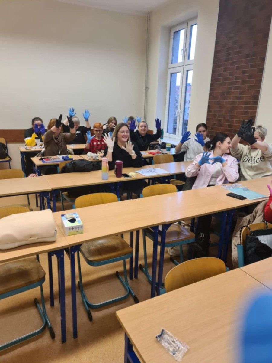 Widok na uczniów w kasie siedzących w łąkach w rękawiczkach.