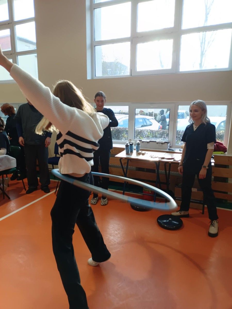 Uczennica bawiąca się hula hop na hali sportowej.